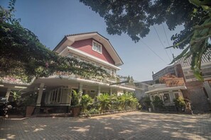 A two-story building with a red roof and a balcony. There are potted plants and a motorcycle parked in front. - Boutique B21 Malang, Azana Hotels Collection (Malang)