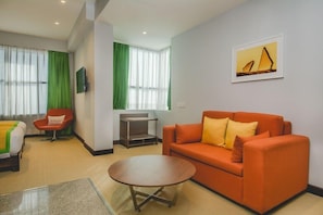 Une chambre d’hôtel moderne équipée d’un canapé, d’une petite table, d’une télévision et d’un lit.
