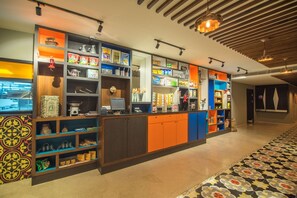 A brightly lit, modern hotel lobby with a central reception desk, colorful shelving units, and patterned floor tiles. - Zone By The Park Jodhpur (Jodhpur)