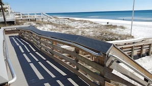 Un muelle de madera que conduce a una playa con vista clara al océano.