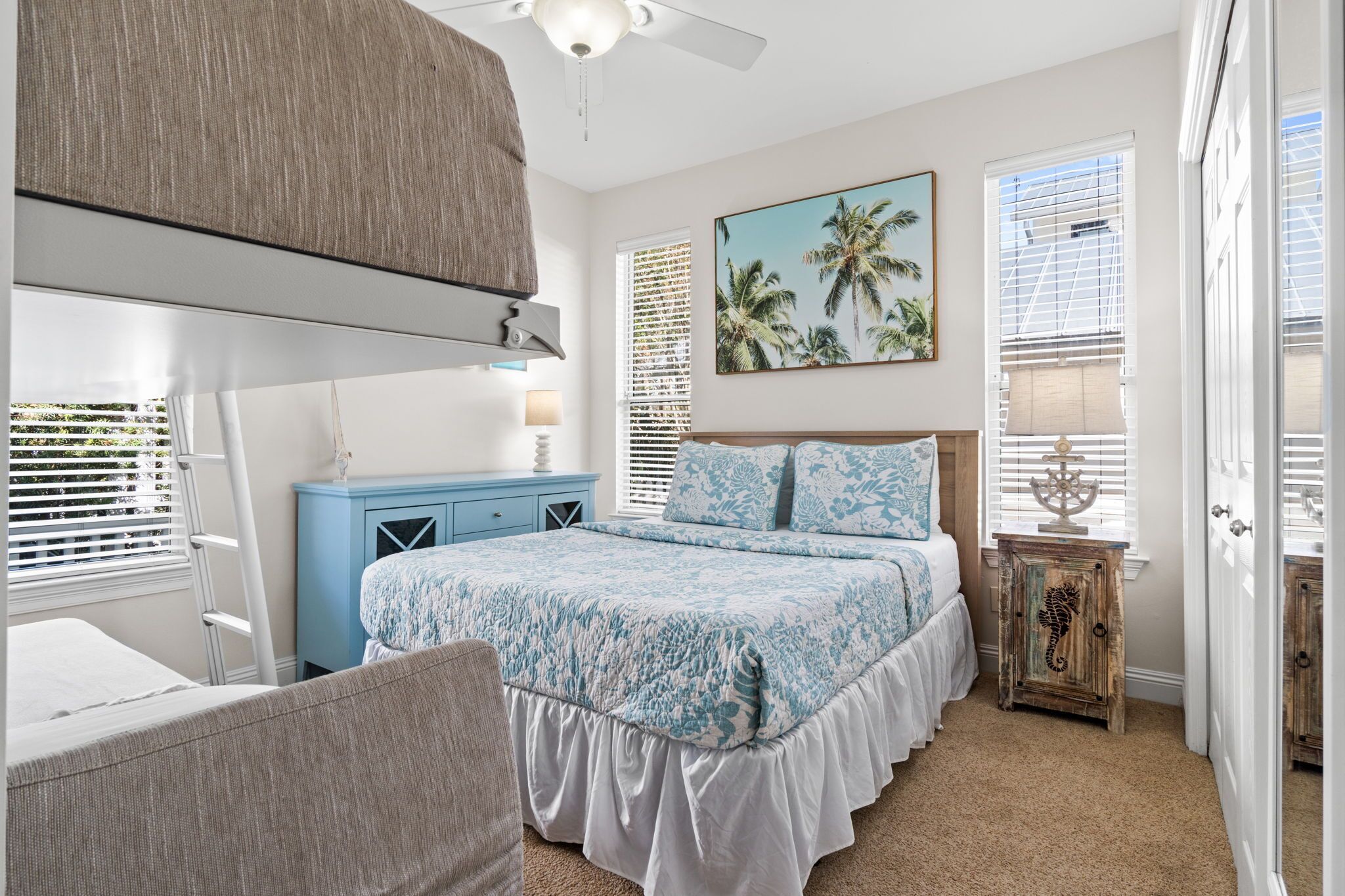 A bedroom with a bed, a nightstand, a chair, a ceiling fan, and a window with blinds.