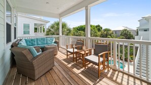 Eine überdachte Terrasse im Freien mit einer Couch, Stühlen und einem Pool.