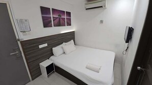 A bedroom with a bed, a nightstand, a wall-mounted air conditioner, and a painting above the bed. - One Point Hotel - RH Plaza (Kuching)