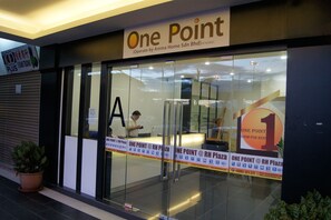 Ein Hotel namens 'One Point' mit Glasfassade, einem Schild mit der Aufschrift 'Zimmer zu vermieten' und einem sichtbaren 'Freie Zimmer'-Schild.