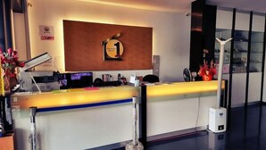 A hotel reception desk with a modern design, a digital screen, and a sign indicating the hotel name. - One Point Hotel - RH Plaza (Kuching)