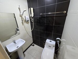 A small bathroom with a white sink, a toilet, and a shower unit. - One Point Hotel - RH Plaza (Kuching)