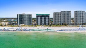A beachfront hotel with multiple high-rise buildings, a sandy beach with umbrellas, and clear turquoise waters. - Beachfront Penthouse~Breath Taking Views~3 King Suites~2 Balconies! (Destin)