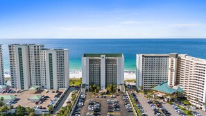 Un complexe hôtelier comprenant plusieurs immeubles de grande hauteur, un parking et offrant une vue sur la plage.