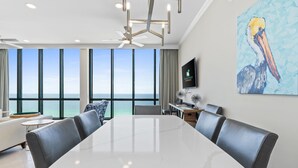 Ein moderner Konferenzraum mit großem Tisch, Ledersesseln, Deckenventilator und einem großen Fenster mit Meerblick.