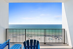 A balcony with a view of a beach, a railing, and blue chairs. - Beachfront Penthouse~Breath Taking Views~3 King Suites~2 Balconies! (Destin)
