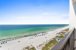 Ein Strand mit Sonnenschirmen und Menschen, ein klarer Himmel und das Meer.