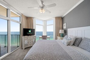 Ein Schlafzimmer mit einem großen Bett, einem Fernseher, einem Deckenventilator und Meerblick.