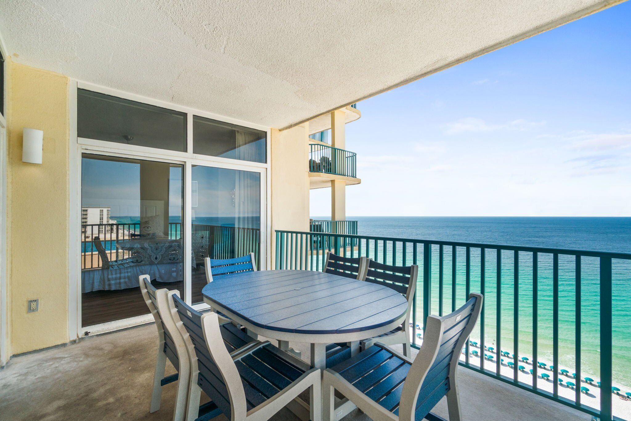 A balcony with a table and chairs, overlooking the ocean.