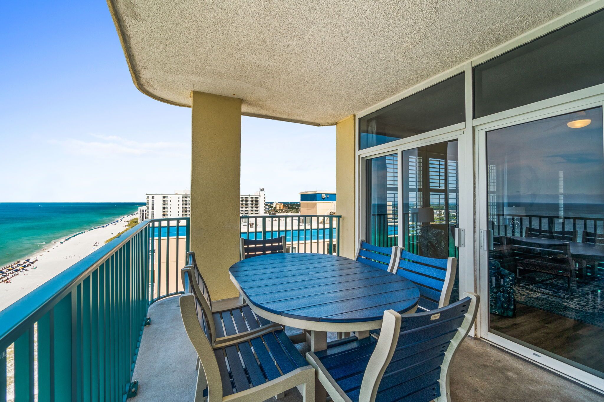 Een balkon met een tafel en stoelen, uitkijkend op een strand.