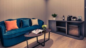 A modern living room with a blue sofa, a coffee table, a fireplace, and a small plant.