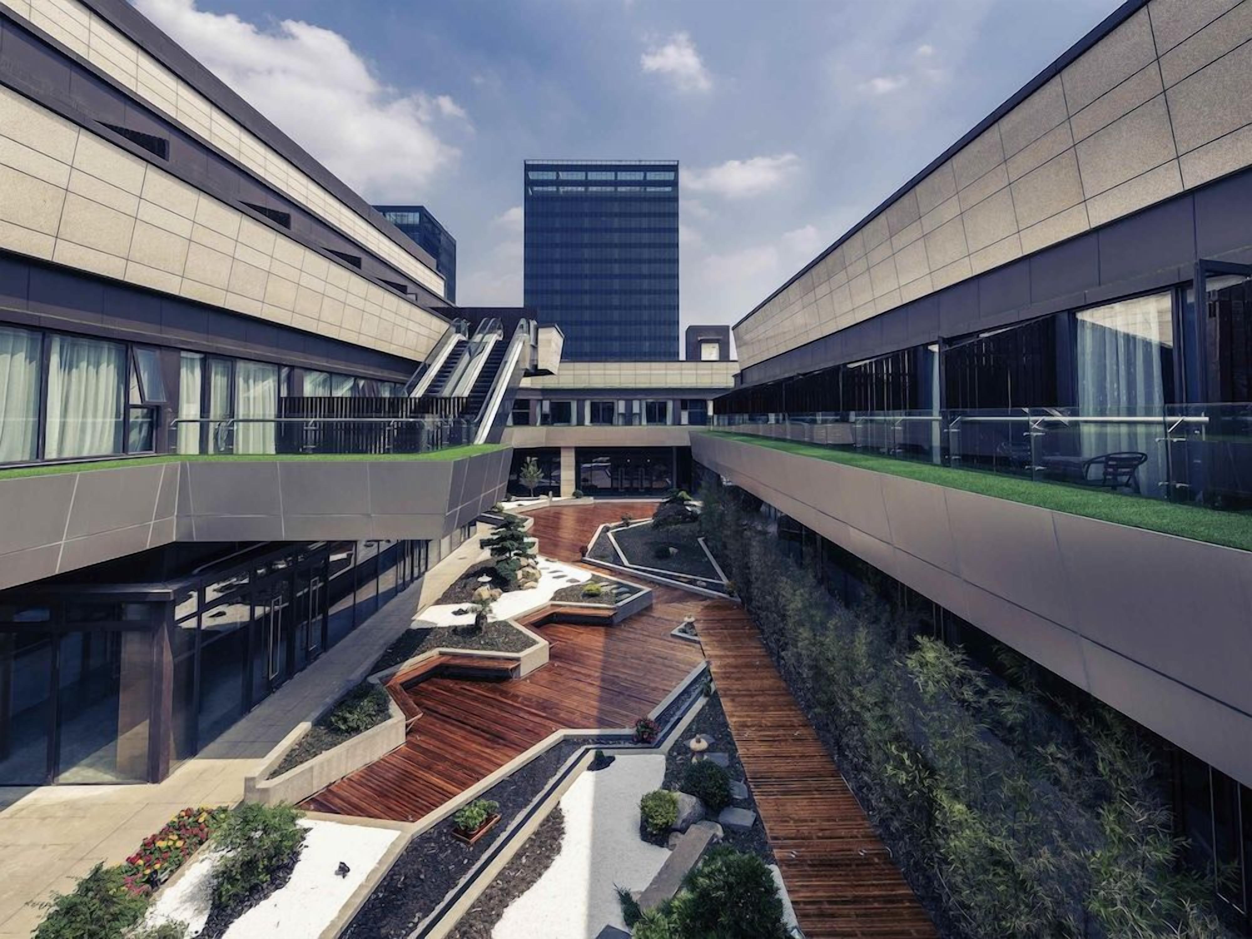 A modern building with a central atrium, glass railings, and a rooftop garden.