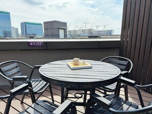 Una terrassa a la teulada amb una taula rodona i cadires, un cartell de 'No s'hi pujada' i una vista panoràmica de la ciutat.
