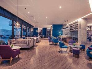 Un interior moderno con zonas de estar, un bar y un amplio ventanal con vista a la calle.