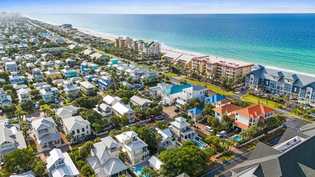 Una zona residencial costera con propiedades frente al mar, un hotel con piscina y una vista despejada del océano.