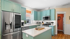 A modern kitchen with teal cabinets, stainless steel appliances, and a central island. - Private Pool, Steps to Beach, Screen in Porch, Cutest Cottage in Crystal Beach! (Destin)
