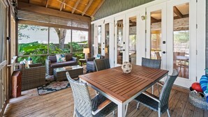 A covered patio with wicker furniture, a wooden table, and a ceiling fan. - Private Pool, Steps to Beach, Screen in Porch, Cutest Cottage in Crystal Beach! (Destin)