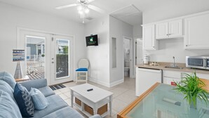 A modern living room with a sofa, coffee table, and a TV mounted on the wall. - Steps to Beach~Private Pool~Pet Friendly~Carriage House~Optional Golf Cart! (Destin)