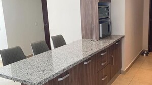 A kitchen with granite countertops, a microwave, and a toaster. There are four chairs and a cabinet with drawers. - Polanco be grand (Ciudad de México)