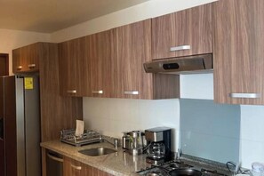 A modern kitchen with wooden cabinets, stainless steel appliances, and a granite countertop. - Polanco be grand (Ciudad de México)