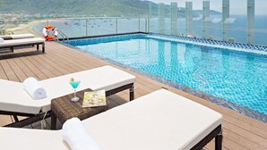 Zona de piscina amb gandules, una beguda i una revista.