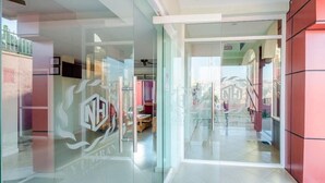 Een moderne hotel lobby met glazen deuren, een receptiebalie en een zichtbare trap.