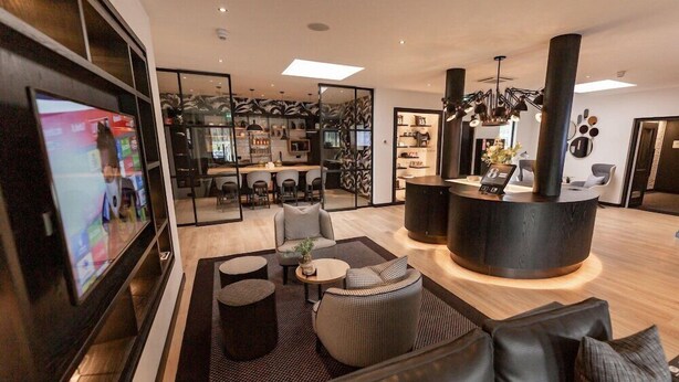 A modern hotel lobby with a bar area, seating arrangements, and a television screen. - Tulip Inn Bodegraven (Bodegraven)