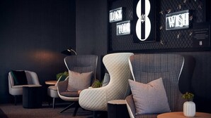 A modern lounge area with three cushioned chairs, a small table, and a decorative wall with illuminated signs. - Tulip Inn Bodegraven (Bodegraven)