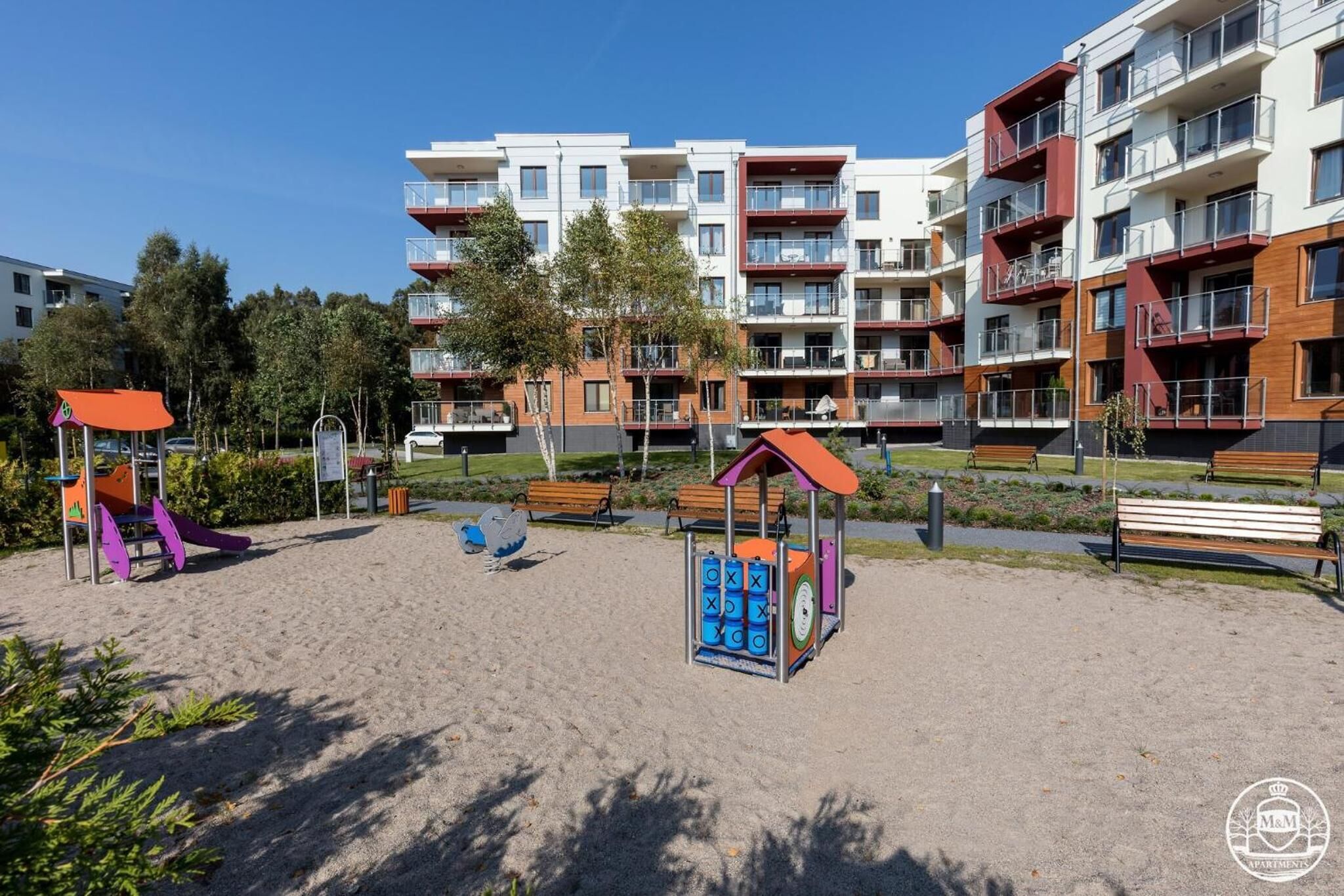 A playground with sand, benches, and a play structure.