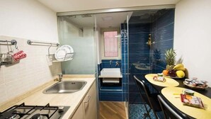 Une cuisine compacte équipée d’une cuisinière à gaz, d’un évier et d’un petit coin repas avec une table et des chaises.
