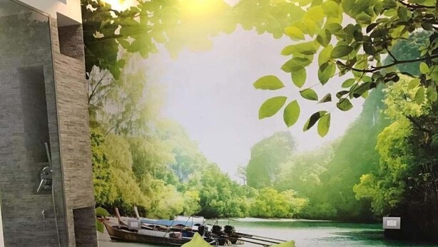 Une chambre à coucher avec un lit, des oreillers verts, une fresque murale représentant une forêt et un plancher en bois.