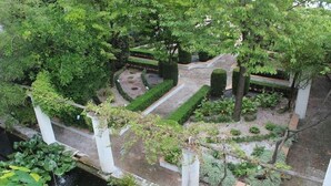 Un jardin bien entretenu, agrémenté de diverses plantes et arbres, avec une zone centrale circulaire constituée de pas japonais et un élément décoratif aquatique en contrebas.