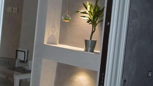 Un couloir étroit doté de trois étagères éclairées, chacune abritant une plante en pot.