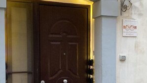 Une porte marron ornée d’un emblème circulaire, une petite fenêtre sur le côté gauche et une pancarte indiquant « SALLE » sur le mur.
