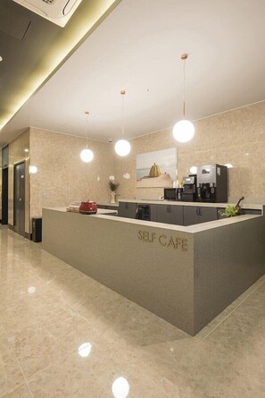 A self-service cafe with a marble countertop, coffee machines, and pendant lighting. - Guseo Station Brown Dot (Busan)