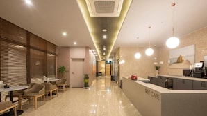 A modern self-service cafe with a clean, minimalist design, featuring a polished floor, a reception area with a counter, and seating arrangements. - Guseo Station Brown Dot (Busan)