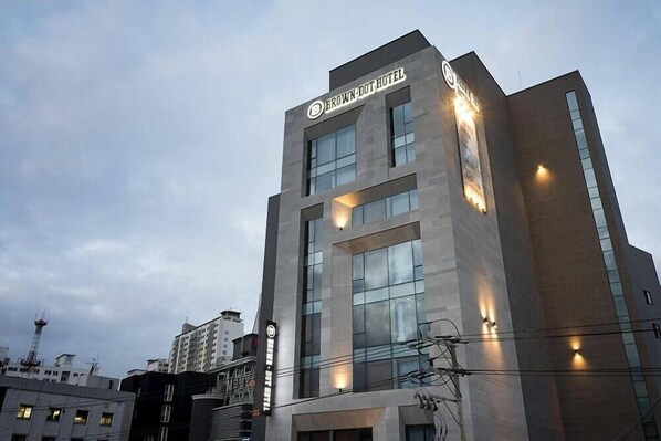 Un hôtel moderne, reconnaissable à son enseigne bien visible où l’on peut lire « BROWN DOT HOTEL ».