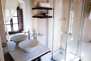 Un baño moderno con un lavabo blanco grande, una cabina de ducha con mampara de vidrio y un perchero sobre el lavabo.
