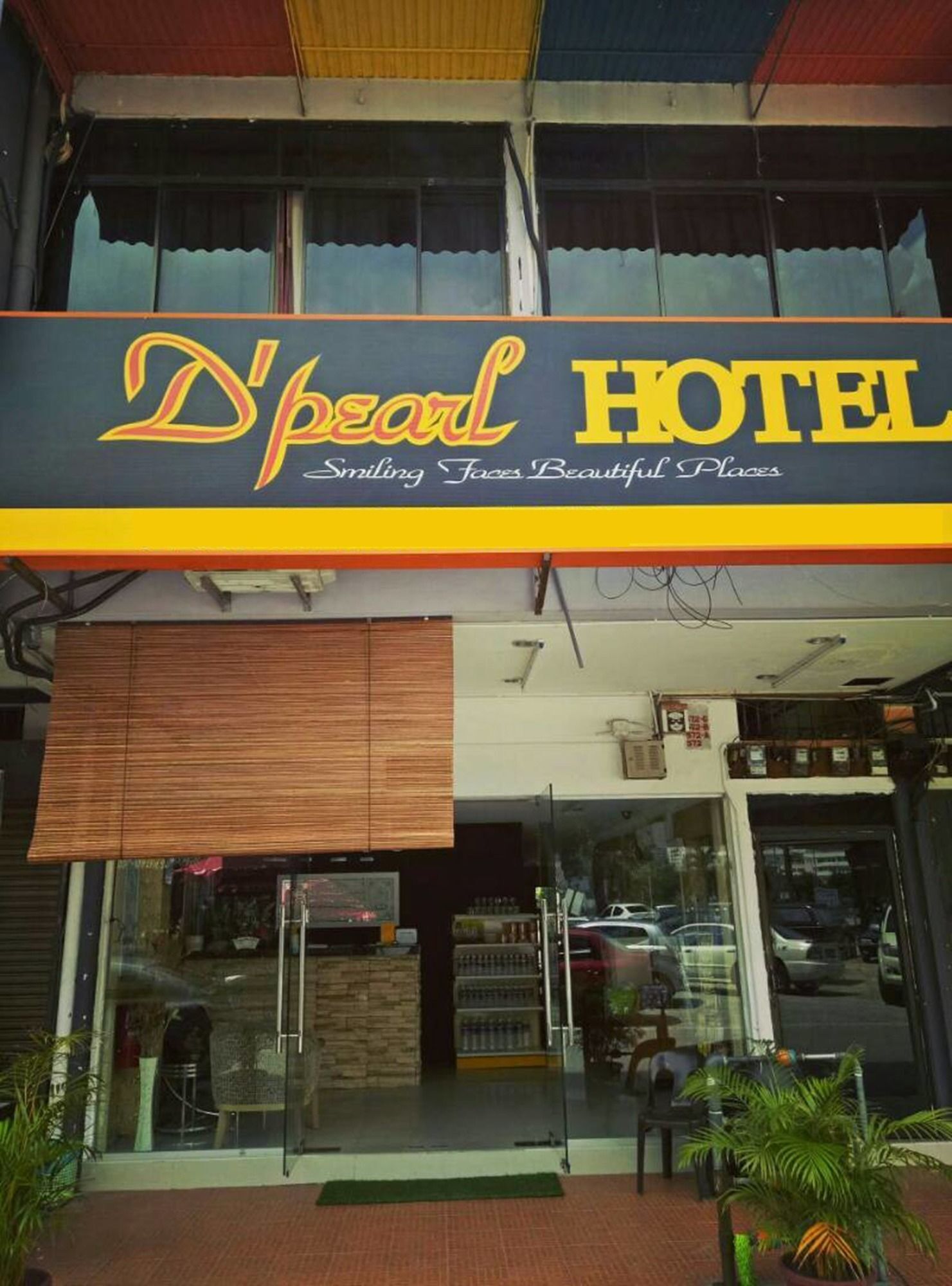 A hotel named 'D'pearl HOTEL' with a sign that reads 'Smiling Faces Beautiful Places'.