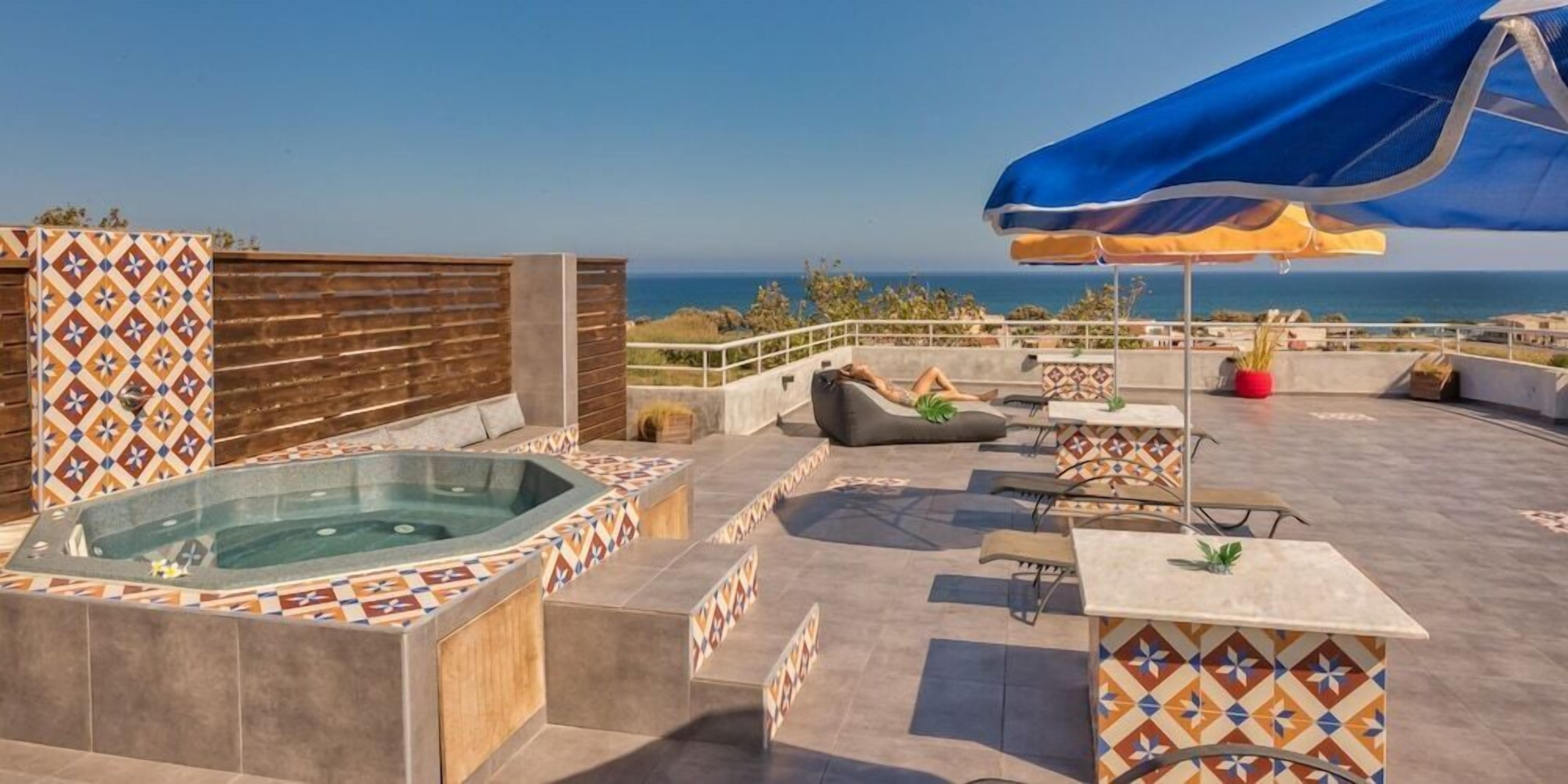 Une terrasse sur le toit avec un jacuzzi, des coins salon et une vue sur la mer.