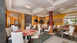 A restaurant with multiple dining tables and chairs, a wine rack, and a television on the wall. - Hotel Mediterraneo (San Vito Lo Capo)