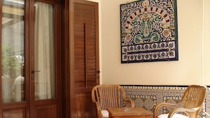 A room with a wooden door, a wall-mounted decorative tile, and a table with two wicker chairs. - Hotel Mediterraneo (San Vito Lo Capo)