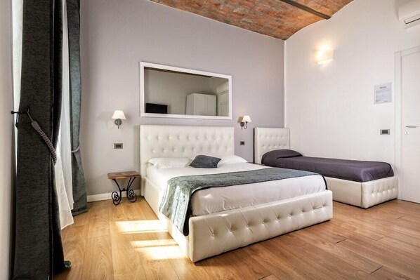 A bedroom with a large bed, a smaller bed, a mirror, and a bedside table. - B&B Chez Moi (Bologna)