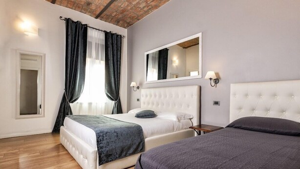 A hotel room with two beds, a large mirror, and a wooden ceiling. - B&B Chez Moi (Bologna)