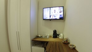 A compact kitchen with a wooden table, a white cabinet, and a television mounted on the wall. - B&B Chez Moi (Bologna)
