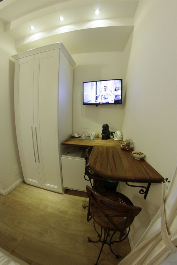 A compact kitchen with a wooden table, a white cabinet, and a television mounted on the wall. - B&B Chez Moi (Bologna)